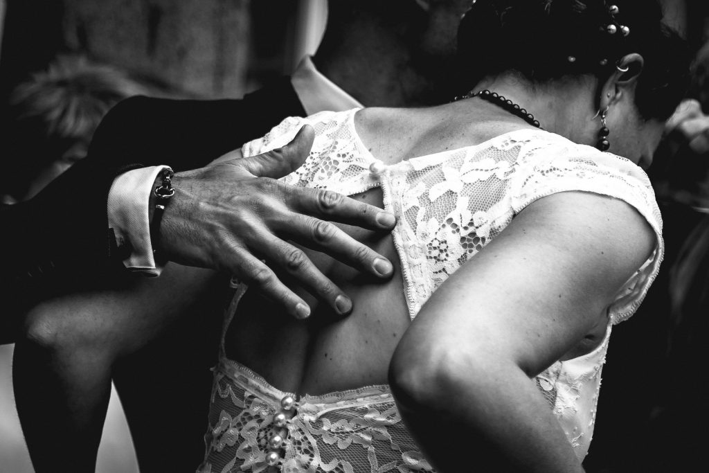 Danse des mariés en noir et blanc, main du marié posée dans le dos de la mariée – photo de mariage naturelle.
