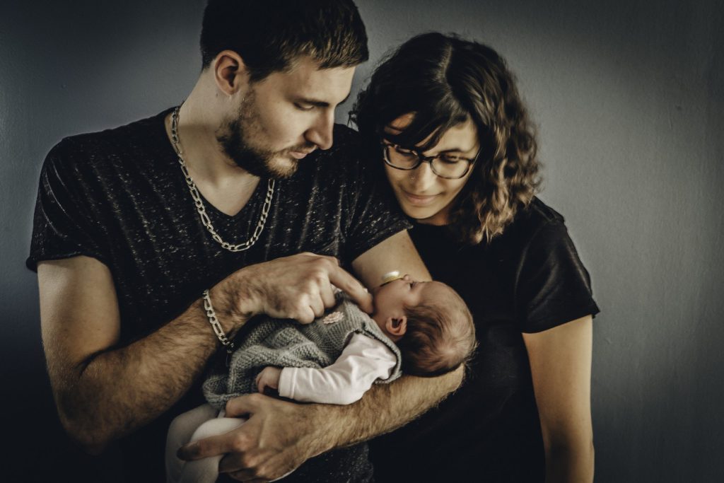 Jeune couple tenant leur nouveau-né dans les bras lors d’une séance photo en famille en studio