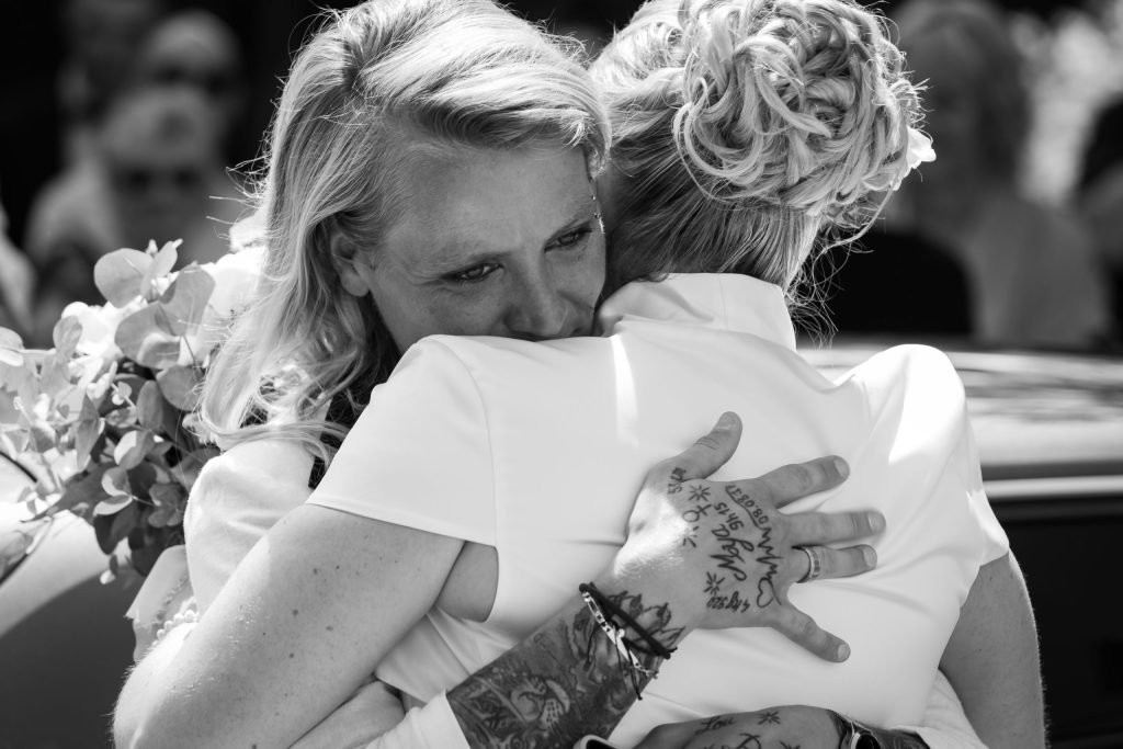 Étreinte chaleureuse entre deux femmes à la sortie d’une cérémonie, moment fort en émotions.