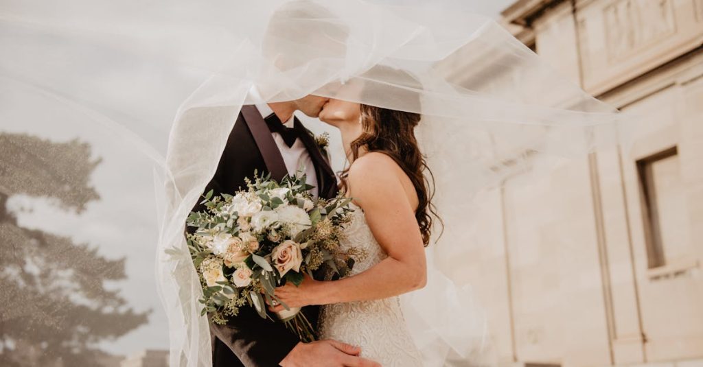 Les mariés partagent un tendre baiser sous un voile, mettant en valeur l'amour et la romance lors de leur journée spéciale.